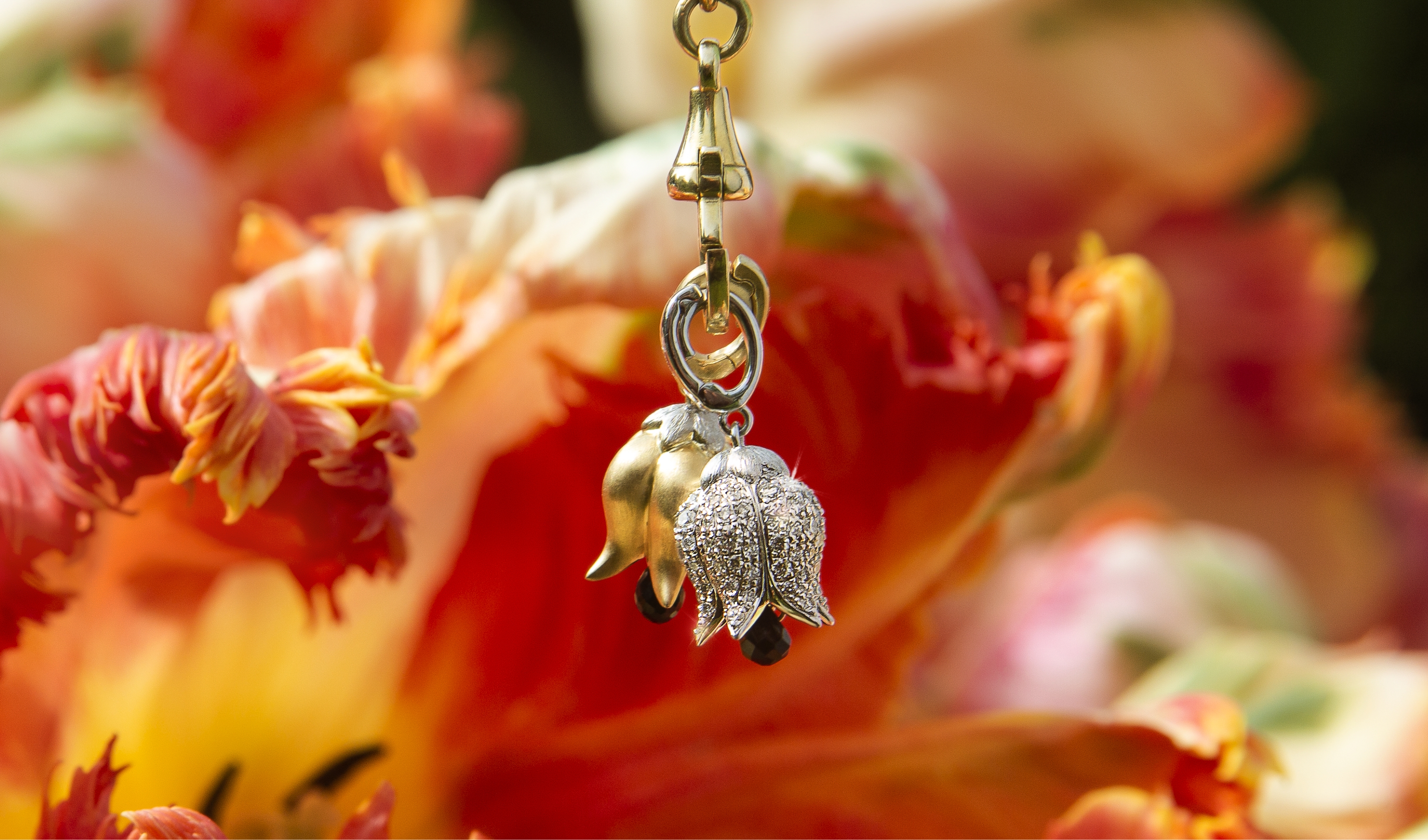 gold and diamond tulip charms in front of tulips