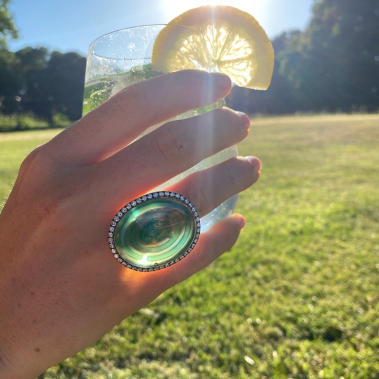 hand holding a drink wearing a cocktail ring 