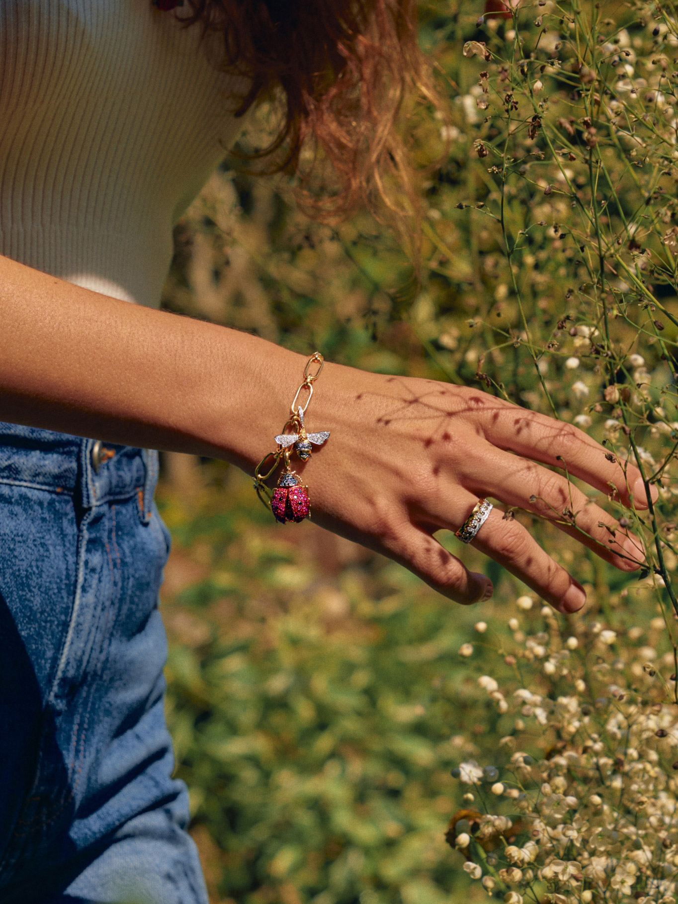 woman's hand with charm bracelet and wild flowers