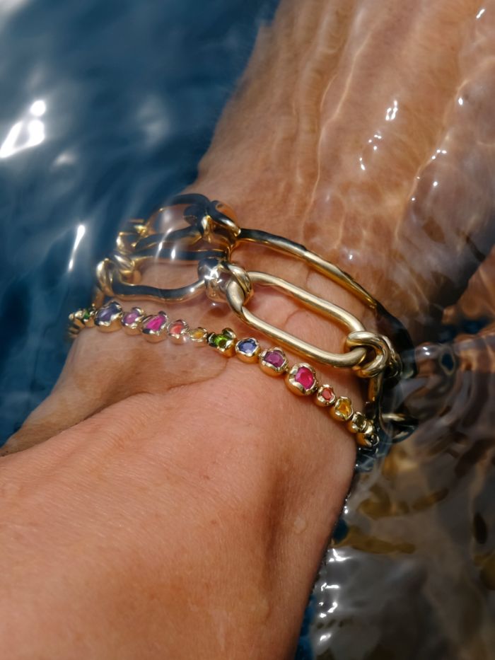 woman's wrist in water wearing gold bracelets 